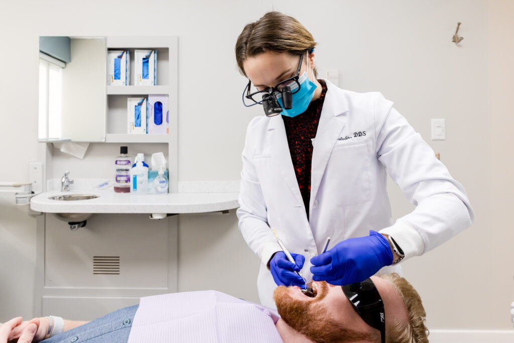 Our dentist with a patient during his routine dental cleaning in Gainesville.